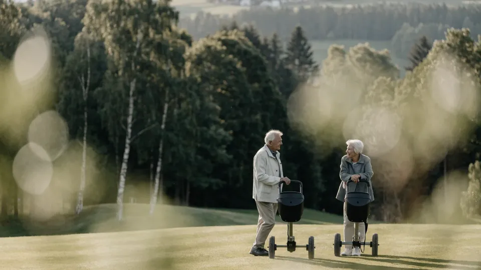 Zwei Senioren mit Trolleys auf dem Fairway